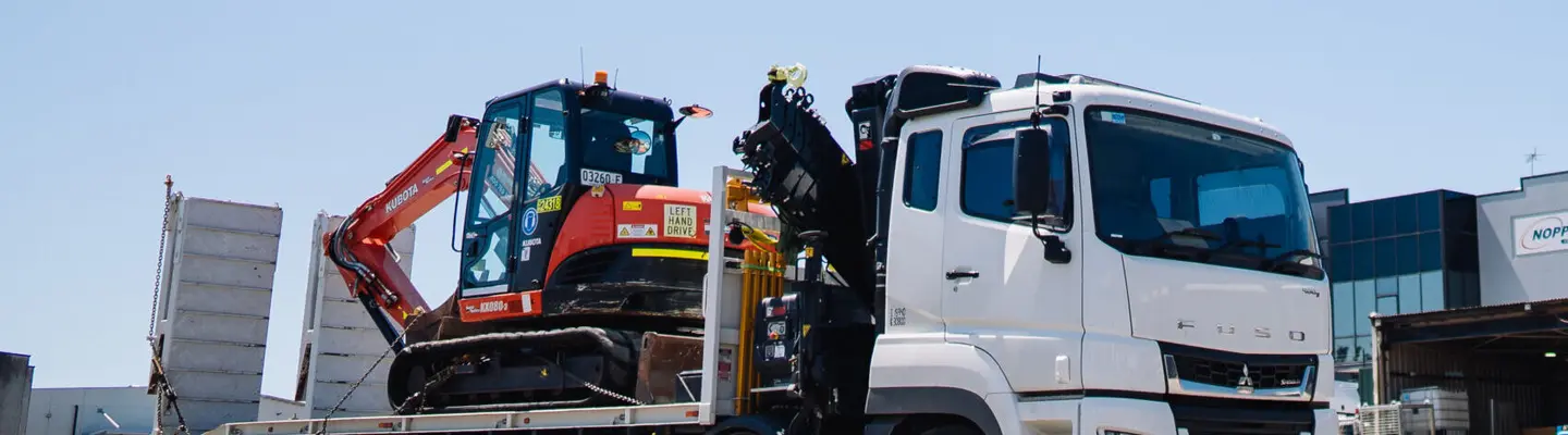 A truck transporting heavy construction equipment, emphasizing logistics and safety at work zones.