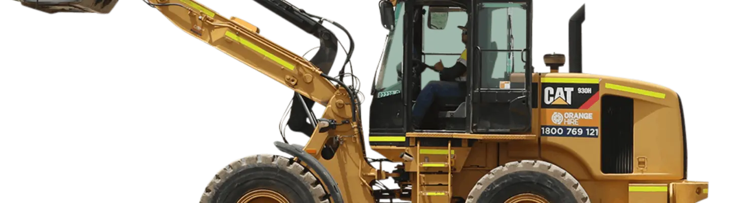 Man driving a backhoe across a construction site, with safety barriers and equipment visible in the background.
