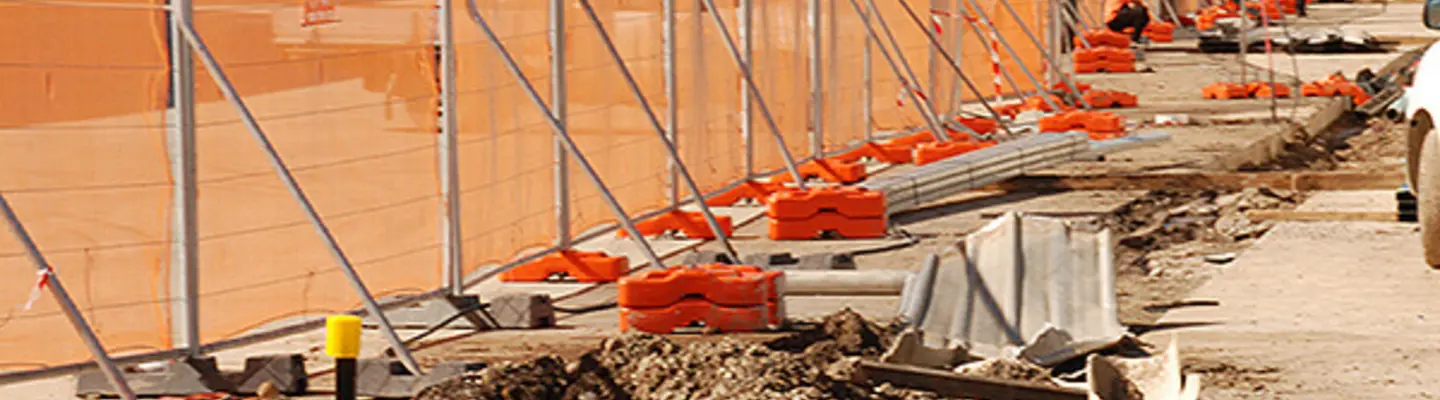 Safety fencing with braces and netting surrounding a construction worksite to prevent debris and unauthorized access.