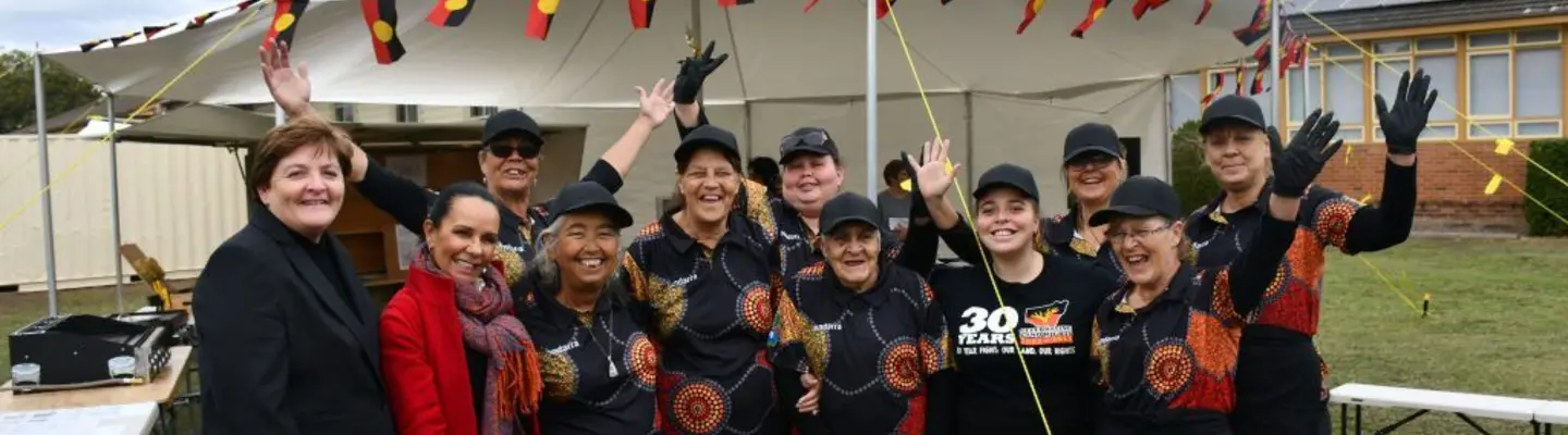  Group of people posing for a photo in front of a mobile home and tent, highlighting a community or outdoor event.
