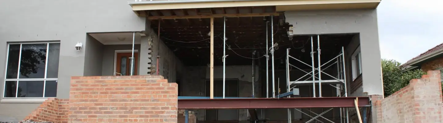 Partially built construction structure supported by props, using lightweight materials for framing and stabilization.