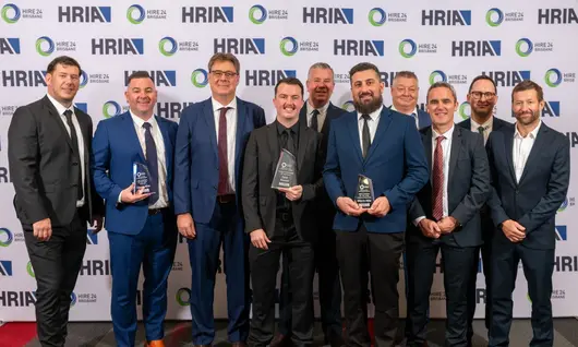 Group of employees smiling and holding an award plaque, celebrating recognition and company achievements.
