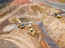 Excavators assisting construction crews on-site, with safety barriers in place to control access and protect workers.